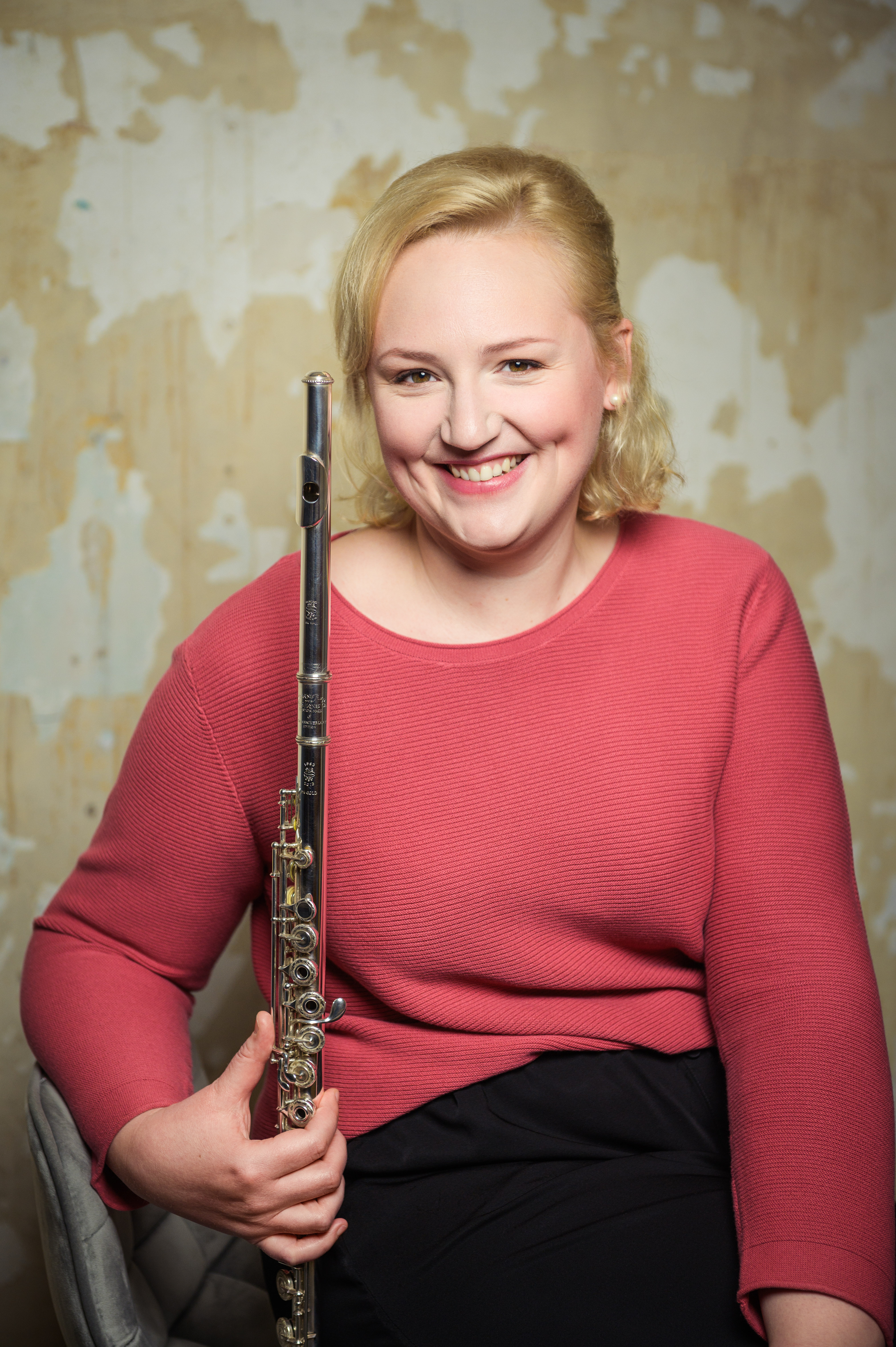 Katharina Sames sitzt auf grauem Stuhl und lächelt